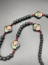 Load image into Gallery viewer, This statement necklace features elegant black matte glass beads with a smooth and velvety finish. Four ornamental ceramic beads with a traditional red, golden, and green pattern create a classic aura and luster-speckled dark red beads bring a striking final touch to the singular look.  This necklace is simple and elegant piece, very versatile look. Perfect cocktail chic attire, fancy wedding necklace, a minimalist look. Necklace: 32” in length   Necklace: 32” in length