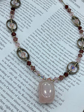 Load image into Gallery viewer, This exquisite necklace features a soft pink Rose Quartz pendant with multi-colored glass beads that transition from iridescent pink, to light purple and darker shades of purple. The sequence of beads complements the Rose Quartz pendant's delicate hue, and is accompanied with a set of subtly-styled matching earrings for a complete look. Measurements: Necklace is 16 1/2”