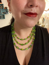 Load image into Gallery viewer, This adjustable glass beaded necklace features a combination of vivid green, blue, and gold hues and a mixture of shapes, creating an eye-catching spectrum of colors and a complex look. The rectangular green glass beads form the predominant part of the three-strand piece, which offers a bold and elegant fashion statement that is ideal for the Spring season. Measurements: Necklace is 17” in length, can be adjusted up to 19" in length