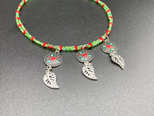 Load image into Gallery viewer, This adjustable necklace features an eye-catching Southwest-inspired design. Multi-hued glass beads, including bright green and vibrant red, are accompanied by dark red and green pendants with silver-plated feather charms. Ideal for chingona guerrera carbonas, la India princesses, warrior cosplay, and native-inspired looks. Measurements: Necklace is 15” adjustable up to 17" in length