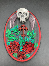 Load image into Gallery viewer, This Memento Mori Wall Art Decor is a one-of-a-kind art piece, skillfully crafted with a black polymer clay skull and wings on a dark red wood frame, decoratively woven with dark red roses and vines. It's perfect for adding an eye-catching touch to any wall and makes a unique, bold gift.  Measurements: H 7" x W 5” x D 1 1/2"