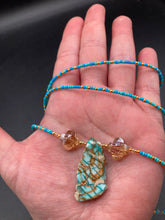 Load image into Gallery viewer, This vibrant and enchanting Southwestern Style inspired necklace is comprised of three strands. The first two feature a mix of blue and green turquoise and gold glass beads, while the longest strand features a howlite stone chip dyed turquoise and shimmery cross faceted champaign color glass beads for a dramatic look. Measurements: The Necklace is 16” and can be adjusted up to 18"