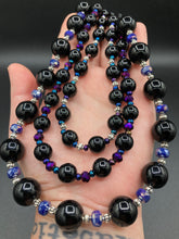 Load image into Gallery viewer, This Bohemian style necklace is composed of three strands of shimmery large black and dark purple glass beads, along with floral metal beads. The elegant drape creates a bold and fierce look that is ideal for a variety of occasions, such as cocktail chic attire and weddings. It is a perfect minimalist accessory.  Measurements:  Necklace is 16” in length - adjustable to 18"