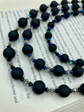 Load image into Gallery viewer, This statement piece features 3 long strands of flat matte black and dark blue glass beads, complemented by a floral metal beaded necklace. It gracefully drapes across the neck for a fierce, yet elegant look, making it perfect for cocktail chic attire, weddings, or minimalist styling.  Measurements:    Necklace is 16” in length - adjustable to 18"
