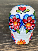 Load image into Gallery viewer, Inspired by nature, ceramic skull is full of vibrant colors and intricate details. The primary color is white with a black cat silhouette and multi-color floral motifs, along with hearts and leaves and lively colorful accents around the entire skull. Mini skull represented the eternal love for a special kitty cat in your life. Black cat silhouette is sitting on a tree branch admiring the starry night sky. Art created for all the cat lovers who adore their sweet kitty. Measurements: H 2 3/4” x W 2” x D 2”