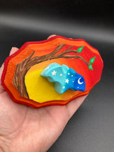 Load image into Gallery viewer, Starry Night Mini Bat Wall Art Decor. A perfect hanging art piece to add a pop of color to your wall, next to your display of crystals or witchy altar. Bat figurine is made of polymer clay, painted ombre colors from light to dark with white stars and crescent moon flying over the sun rise sky. Orange and red wood frame matches the light yellow, orange and red sky. Art come ready to hang with a sawtooth hangers on back. Measurements: H 3" x W 5” x D 1 1/2"