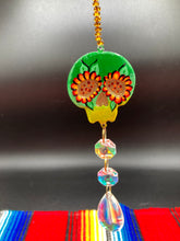 Load image into Gallery viewer, Nature inspired hand crafted polymer clay skull is painted in ombre colors from dark green to light yellow and decorated with flowers on back and over eyes. Light gold glass beaded chain with iridescent crystals. A perfect hanging Day of the Dead art piece to add to your ofrenda, hang next to your display of crystals or witchy altar, add to your skull collection or hang as an art piece on the wall or near a window. Measurements: H 1 1/2” x W 1 1/2” x D 3/4”