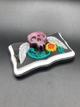 Load image into Gallery viewer, This unique wall art decor, crafted with hand-molded polymere clay and painted on a wooden frame, brings to life a classic Dia De Los Muertos Calavera with its fiery-red skull and bright yellow-orange flower and vine accents. Perfect for accenting your crystal display, witchy altar, or indoor garden.
