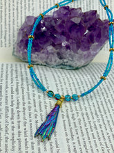 Load image into Gallery viewer, This Rainbow Kyanite Natural Wired Stone Choker Style Necklace presents two strands of light blue glass beads, and is adorned with a Kyanite stone known for its shimmering array of pink, gold, blue, and green hues. Providing a bold and attention-grabbing look, this piece of Hippie Crystal Jewelry is a must-have addition to any wardrobe. Necklace is 17 1/2” in length