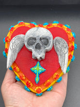 Load image into Gallery viewer, This Memento Mori Wall Art Decor is a unique statement piece to add a pop of color to your walls. Handcrafted with black and white polymer clay, acrylic paint, and a wood frame, the skull artwork is decorated with small turquoise and yellow-orange flowers and a turquoise and gold cross. Perfect for a Day of the Dead altar or a witchy home decor display.