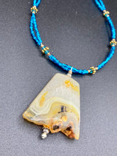 Load image into Gallery viewer, This two-strand necklace features an array of glass beads, including shades of green, blue and turquoise, as well as gold and green. Topped off with a show-stopping yellow agate stone in turquoise, the necklace boasts an eye-catching color combination. Measurements: Necklace is 15 1/2", adjustable up to 17”