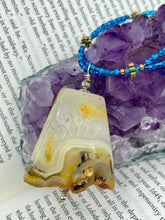 Load image into Gallery viewer, This two-strand necklace features an array of glass beads, including shades of green, blue and turquoise, as well as gold and green. Topped off with a show-stopping yellow agate stone in turquoise, the necklace boasts an eye-catching color combination. Measurements: Necklace is 15 1/2", adjustable up to 17”