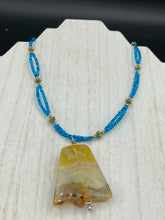 Load image into Gallery viewer, This two-strand necklace features an array of glass beads, including shades of green, blue and turquoise, as well as gold and green. Topped off with a show-stopping yellow agate stone in turquoise, the necklace boasts an eye-catching color combination. Measurements: Necklace is 15 1/2", adjustable up to 17”