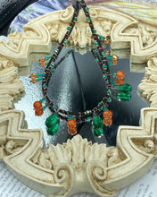 Load image into Gallery viewer, This necklace is the perfect addition to any collection, boasting a dark, elegant aesthetic inspired by nature. Comprised of two strands of glass beads with a variety of shapes and colors, it offers subtle autumnal vibrancy with its orange and green pumpkin-shaped glass beads. This piece is full of shimmer and complexity, providing unique depth and flair. Necklace is 16 1/2” in length, can be adjusted up to 18 1/2"