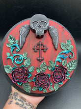 Load image into Gallery viewer, This Memento Mori Wall Art Decor is a one-of-a-kind art piece, skillfully crafted with a black polymer clay skull and wings on a dark red wood frame, decoratively woven with dark red roses and vines. It's perfect for adding an eye-catching touch to any wall and makes a unique, bold gift.  Measurements:  Diameter 6 3/4" x Depth 1 1/2"
