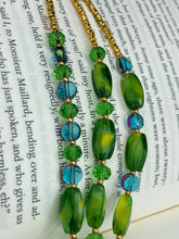 Load image into Gallery viewer, This adjustable glass beaded necklace features a combination of vivid green, blue, and gold hues and a mixture of shapes, creating an eye-catching spectrum of colors and a complex look. The rectangular green glass beads form the predominant part of the three-strand piece, which offers a bold and elegant fashion statement that is ideal for the Spring season. Measurements: Necklace is 17” in length, can be adjusted up to 19" in length