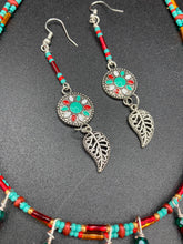 Load image into Gallery viewer, This two-strand adjustable necklace features a culturally inspired design with vibrant green turquoise, bright red, orange, green and gold glass beads, accompanied by silver plated feather charms that create a unique sense of motion. An ideal accessory for summer styles, this native tribal pattern necklace and matching earrings set will perfectly complete any ensemble. Measurements: Necklace: 15 3/4” adjustable up to 18" in length