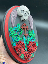 Load image into Gallery viewer, This Memento Mori Wall Art Decor is a one-of-a-kind art piece, skillfully crafted with a black polymer clay skull and wings on a dark red wood frame, decoratively woven with dark red roses and vines. It's perfect for adding an eye-catching touch to any wall and makes a unique, bold gift.  Measurements: H 7" x W 5” x D 1 1/2"