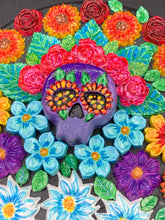 Load image into Gallery viewer, Frida Kahlo inspired calavera with a black wood frame, this Day of the Dead wall decor piece is perfect for adding a traditional Mexican folk art touch to any home. Add a unique touch of style to your home with this intricately detailed, Frida Kahlo-inspired calavera clay wall art. The design features an eye-catching crown of flowers, plus a vibrant bouquet, perfect for any Day of the Dead celebration. Bring a bright and colorful piece of art to your home with this stunning wall hanging.