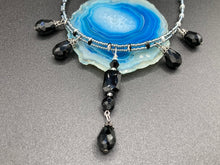 Load image into Gallery viewer, This adjustable collar-style necklace features silver and black glass beads in a combination of both teardrop and rectangular shapes, designed to create visual complexity and depth. The two strands are held together with two-hole silver and black beads, creating a stunningly bold and elegant draped collar that enhances any outfit.