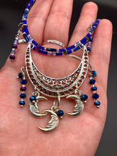 Load image into Gallery viewer, This stylish choker necklace showcases a large half moon pendant, adorned with glass beads and small, dangling crescent moon charms. Its eye-catching hues, of blue and silver, are complemented with delicate tints of purple and pink. Boasting an accentuated look and ample motion, this piece is sure to impress. Measurements: Necklace is 16 1/2”adjustable up to 18"