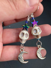 Load image into Gallery viewer, Galaxy Cosmos Stardust Howlite Skull Bead Earrings - star shaped rainbow hematite beads and smiling crescent moons. These pair of earrings have a lot of movement and shimmer for that witchy vibe. You can dress these up or down, it will definitely give your outfit a unique look. Measurements: 2 ” in length