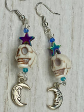 Load image into Gallery viewer, Galaxy Cosmos Stardust Howlite Skull Bead Earrings - star shaped rainbow hematite beads and smiling crescent moons. These pair of earrings have a lot of movement and shimmer for that witchy vibe. You can dress these up or down, it will definitely give your outfit a unique look. Measurements: 2 ” in length