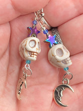 Load image into Gallery viewer, Galaxy Cosmos Stardust Howlite Skull Bead Earrings - star shaped rainbow hematite beads and smiling crescent moons. These pair of earrings have a lot of movement and shimmer for that witchy vibe. You can dress these up or down, it will definitely give your outfit a unique look. Measurements: 2 ” in length
