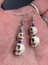 Load image into Gallery viewer, Mini Howlite Skull Bead Earrings, two tiny skull bead stacked set of earrings with shimmery blue glass beads in between each skull to give these cuties some sparkle. Perfect for any goth, emo, witchy, day of the dead outfit. You can dress these up or down, it will definitely give your outfit a unique look. Measurements: 1 ” in length