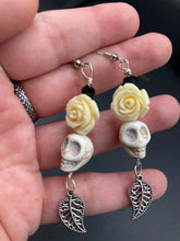 Load image into Gallery viewer, Frida Kahlo Inspired Earrings, Howlite Skull And White Quartize Floral Beads. This beautifully and elegant set of earrings captures Frida Kahlo's signature floral crown on her head. Dangling silver plated intricate leaf at the bottom to give these earrings some movement. These are a beautiful piece of jewelry to wear for inspiration or a great Dia De Los Muertos jewelry piece. Chingona, Cabrona, Latina Chicana, Goth, Vampire Goth, Dark Witchy Style. 2 ” in length