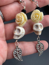 Load image into Gallery viewer, Frida Kahlo Inspired Earrings, Howlite Skull And White Quartize Floral Beads. This beautifully and elegant set of earrings captures Frida Kahlo's signature floral crown on her head. Dangling silver plated intricate leaf at the bottom to give these earrings some movement. These are a beautiful piece of jewelry to wear for inspiration or a great Dia De Los Muertos jewelry piece. Chingona, Cabrona, Latina Chicana, Goth, Vampire Goth, Dark Witchy Style. 2 ” in length