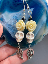 Load image into Gallery viewer, Frida Kahlo Inspired Earrings, Howlite Skull And White Quartize Floral Beads. This beautifully and elegant set of earrings captures Frida Kahlo's signature floral crown on her head. Dangling silver plated intricate leaf at the bottom to give these earrings some movement. These are a beautiful piece of jewelry to wear for inspiration or a great Dia De Los Muertos jewelry piece. Chingona, Cabrona, Latina Chicana, Goth, Vampire Goth, Dark Witchy Style. 2 ” in length