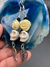Load image into Gallery viewer, Frida Kahlo Inspired Earrings, Howlite Skull And White Quartize Floral Beads. This beautifully and elegant set of earrings captures Frida Kahlo's signature floral crown on her head. Dangling silver plated intricate leaf at the bottom to give these earrings some movement. These are a beautiful piece of jewelry to wear for inspiration or a great Dia De Los Muertos jewelry piece. Chingona, Cabrona, Latina Chicana, Goth, Vampire Goth, Dark Witchy Style. 2 ” in length
