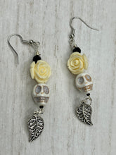 Load image into Gallery viewer, Frida Kahlo Inspired Earrings, Howlite Skull And White Quartize Floral Beads. This beautifully and elegant set of earrings captures Frida Kahlo's signature floral crown on her head. Dangling silver plated intricate leaf at the bottom to give these earrings some movement. These are a beautiful piece of jewelry to wear for inspiration or a great Dia De Los Muertos jewelry piece. Chingona, Cabrona, Latina Chicana, Goth, Vampire Goth, Dark Witchy Style. 2 ” in length