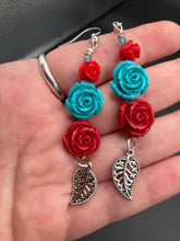 Load image into Gallery viewer, Alluring and enchanting southwest inspired dainty set of earrings captures the beauty of the desert full of blue turquoise and bright red colors, highly detailed and vibrant quartize rose beads and intricate silver plated leaf gives a fun movement. Perfect for you southwest nature lovers, Dia De Los Muertos, . You can dress these up or down, it will definitely give your outfit a unique look. Measurements: 2 1/2” in length