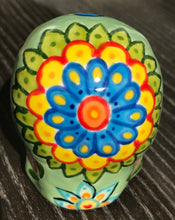 Load image into Gallery viewer, Inspired by nature, this ceramic skull statuette is full of vibrant color and intricate details. The primary color is soft, light periwinkle blue with Multi-color floral motifs that are painted across the skull, along with hearts and leaves and lively colorful accents around the entire skull.