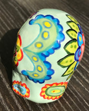 Load image into Gallery viewer, This Mini Light Green Dia De Los Muertos Hand Painted Ceramic Sugar Skull is a unique and vibrant piece of art. Its soft mint green base is filled with beautiful, detailed motifs of nature, such as colorful floral designs, hearts, and leaves. Perfect as an altar decoration or to add a fun, gothic touch to any space. Measurements: H 2 3/4” x W 2” x D 2”