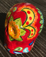 Load image into Gallery viewer, This ceramic skull statuette is a stunning piece of art inspired by nature. Its vibrant red hue is decorated with multi-color floral motifs, hearts, leaves and colorful accents, creating a beautiful piece of hand-painted, Day of the Dead-themed art. Measurements: H 2 3/4” x W 2” x D 2”