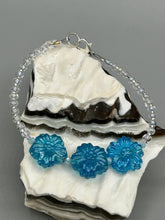 Load image into Gallery viewer, This light blue pressed glass floral bracelet is a sophisticated addition to any summer look. Its iridescent shimmer finish adds a classy touch to its intricate metal wire and lobster claw clasp. Perfect for any nature-inspired wardrobe. Measurements: Bracelet: 8" in length
