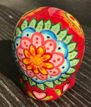 Load image into Gallery viewer, This ceramic skull statuette is a stunning piece of art inspired by nature. Its vibrant red hue is decorated with multi-color floral motifs, hearts, leaves and colorful accents, creating a beautiful piece of hand-painted, Day of the Dead-themed art. Measurements: H 2 3/4” x W 2” x D 2”