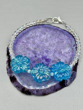 Load image into Gallery viewer, This light blue pressed glass floral bracelet is a sophisticated addition to any summer look. Its iridescent shimmer finish adds a classy touch to its intricate metal wire and lobster claw clasp. Perfect for any nature-inspired wardrobe. Measurements: Bracelet: 8" in length