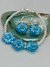 Load image into Gallery viewer, This light blue pressed glass floral bracelet is a sophisticated addition to any summer look. Its iridescent shimmer finish adds a classy touch to its intricate metal wire and lobster claw clasp. Perfect for any nature-inspired wardrobe. Measurements: Bracelet: 8" in length Earrings: 1 1/4" length