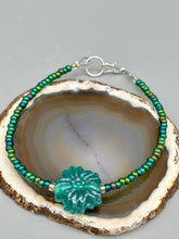 Load image into Gallery viewer, This blue-green pressed glass floral beaded bracelet is a nature-inspired accessory that adds a hint of summer to any look. Crafted with intricate green-blue pressed glass beads and metal wire, the bracelet has an iridescent shimmer finish and a lobster claw clasp for secure wear. Perfect for day-to-night looks. Measurements:  Bracelet: 8 1/2" in length   Earrings: 1 1/4" length
