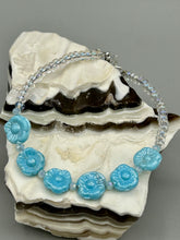Load image into Gallery viewer, Light blue pressed glass bracelet featuring floral beading is detailed with an iridescent shimmer finish. The bracelet is crafted with metal wire and a lobster claw clasp for easy and secure fastening. Measurements: Bracelet: 8 1/4" in length