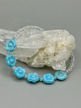 Load image into Gallery viewer, Light blue pressed glass bracelet featuring floral beading is detailed with an iridescent shimmer finish. The bracelet is crafted with metal wire and a lobster claw clasp for easy and secure fastening. Measurements: Bracelet: 8 1/4" in length