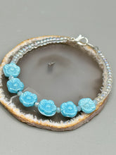 Load image into Gallery viewer, Light blue pressed glass bracelet featuring floral beading is detailed with an iridescent shimmer finish. The bracelet is crafted with metal wire and a lobster claw clasp for easy and secure fastening. Measurements: Bracelet: 8 1/4" in length