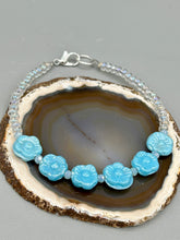 Load image into Gallery viewer, Light blue pressed glass bracelet featuring floral beading is detailed with an iridescent shimmer finish. The bracelet is crafted with metal wire and a lobster claw clasp for easy and secure fastening. Measurements: Bracelet: 8 1/4" in length