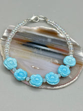 Load image into Gallery viewer, Light blue pressed glass bracelet featuring floral beading is detailed with an iridescent shimmer finish. The bracelet is crafted with metal wire and a lobster claw clasp for easy and secure fastening. Measurements: Bracelet: 8 1/4" in length