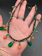 Load image into Gallery viewer, This necklace is the perfect addition to any collection, boasting a dark, elegant aesthetic inspired by nature. Comprised of two strands of glass beads with a variety of shapes and colors, it offers subtle autumnal vibrancy with its orange and green pumpkin-shaped glass beads. This piece is full of shimmer and complexity, providing unique depth and flair. Necklace is 16 1/2” in length, can be adjusted up to 18 1/2"