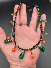 Load image into Gallery viewer, This necklace is the perfect addition to any collection, boasting a dark, elegant aesthetic inspired by nature. Comprised of two strands of glass beads with a variety of shapes and colors, it offers subtle autumnal vibrancy with its orange and green pumpkin-shaped glass beads. This piece is full of shimmer and complexity, providing unique depth and flair. Necklace is 16 1/2” in length, can be adjusted up to 18 1/2"